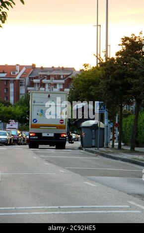 Tôt le matin, la collecte automatique des déchets des poubelles en plastique situées sur le bord de la rue vers un gros camion de déchets garés vu de derrière tôt le matin Banque D'Images