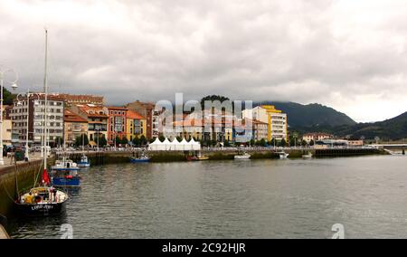 Front de mer à Ribadesella Asturias Espagne avec des bateaux de pêche amarrés dans un après-midi d'été nuageux Banque D'Images