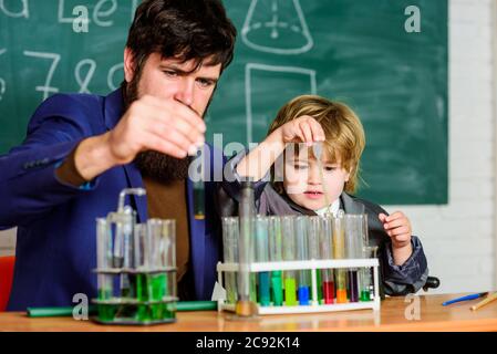 Programme scolaire. Garçon d'école mignon enfant expérimentant avec des liquides. Tubes à essai pour enseignants et enfants. Leçon scolaire. La persévérance paye. Expérience chimique. Symptômes du TDAH à l'école. Banque D'Images