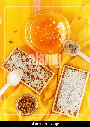 Produits d'abeille : miel, perga, nid d'abeille sur fond orange doré avec cadre transparent Banque D'Images