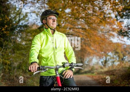 Homme mûr à vélo sur route de campagne d'automne Banque D'Images