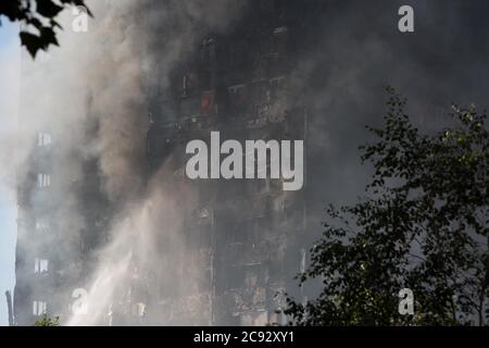 De la fumée s'élève à l'incendie de la Grenfell Tower, un immeuble de 24 étages faisant partie du Lancaster West Estate à North Kensington, Londres, Royaume-Uni. L'incendie a été déclenché tôt le matin par un réfrigérateur-congélateur défectueux au quatrième étage. Il s'étend rapidement à l'extérieur du bâtiment, par le revêtement extérieur et l'isolation. L'incendie a causé 72 morts, dont ceux de deux victimes qui sont plus tard décédées à l'hôpital. Plus de 70 autres personnes ont été blessées et 223 personnes ont échappé. C'était le feu structurel le plus meurtrier du Royaume-Uni depuis 1988 et le pire incendie résidentiel britannique depuis la Seconde Guerre mondiale Banque D'Images