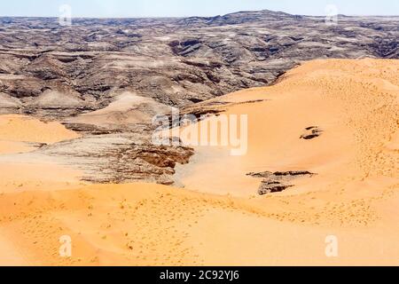 Terrain montagneux typique sombre et aride du désert de Namib avec sable ocre sur une roche stratifiée sur la côte de Skeleton, Namibie, Afrique du Sud-Ouest Banque D'Images