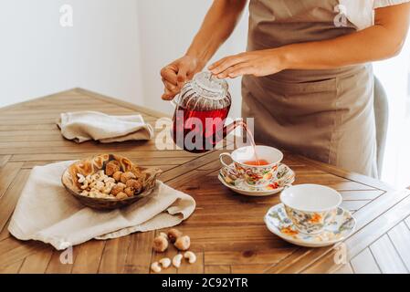 Section médiane de la femme versant du thé hibiscus dans des tasses sur la table Banque D'Images