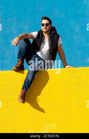 Homme barbu en t-shirt blanc, veste et Jean sur fond bleu Banque D'Images