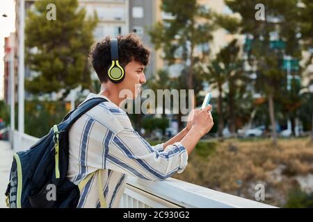 Le jeune homme aux cheveux afro-hachis utilise son smartphone et écoute musique Banque D'Images