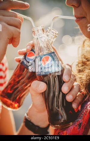 ODESSA, UKRAINE - 15 OCTOBRE 2014 : gros plan de jeunes couples heureux à l'extérieur de boire froid Pepsi à partir de bouteilles de verre avec de la paille Banque D'Images