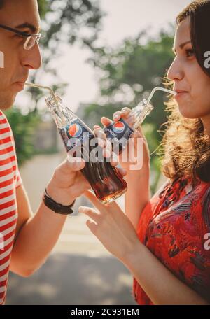 ODESSA, UKRAINE - 15 OCTOBRE 2014 : gros plan de jeunes couples heureux à l'extérieur de boire froid Pepsi à partir de bouteilles de verre avec de la paille et regardant chacun Banque D'Images