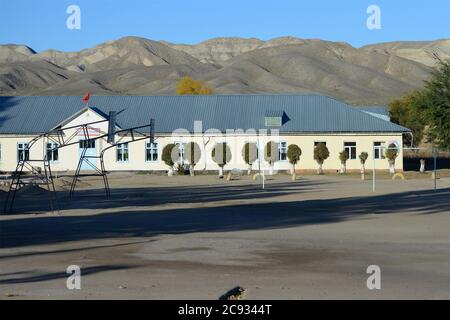 École primaire à Kara-Koo, un petit village de la région d'Issyk-Kul, dans la campagne du Kirghizistan. Zone de sport vide visible. Petit bâtiment d'éducation. Banque D'Images