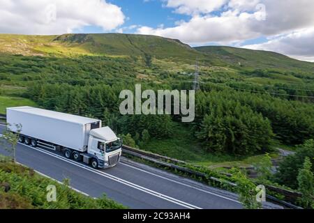Un camion DAF tire une remorque à conteneur à corps d'acier le long de l'A628 Woodhead Pass dans le Yorkshire lors d'un après-midi ensoleillé d'été Banque D'Images