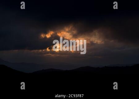 Nuages rouges dans un paysage de montagne sombre à la tombée de la nuit Banque D'Images