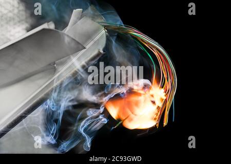Câbles électriques de couleur flamboyante dans les épaves endommagées sur fond noir. Incendie de câblage dans des pièces métalliques ou en plastique. Collision aérienne ou ferroviaire. Banque D'Images