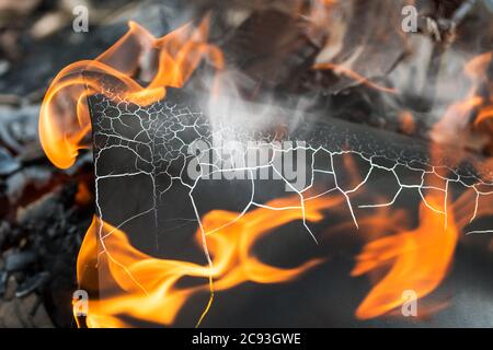 Épave noire de charbon dans le feu et la fumée. Détail conflagration abstrait. Détail artistique des flammes orange flamboyantes sur la peinture fissurée de la tôle en feu. Banque D'Images