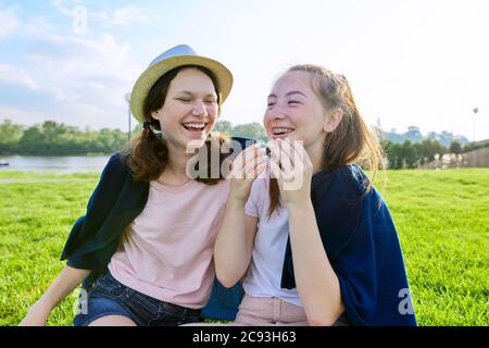 Petites amies adolescents s'amusant assis sur l'herbe le jour ensoleillé de l'été Banque D'Images