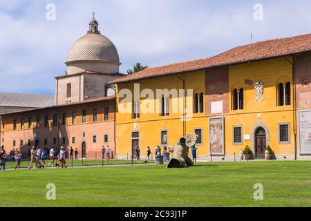 Pise, Italie - 14 août 2019 : Palazzo dell'Opera ou Palais de l'Opéra et la sculpture d'ange déchu sur la Piazza dei Miracoli ou la place des miracles à Pise Banque D'Images