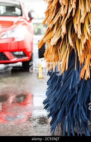 Détail de la brosse de lavage de voiture sur la machine automatique. Voiture utilitaire rouge. Banque D'Images