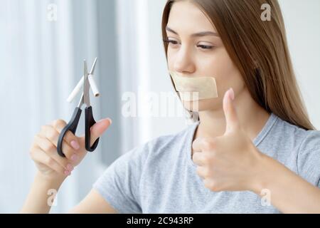Arrêtez de fumer, une femme avec une bouche scellée tenant une cigarette cassée Banque D'Images