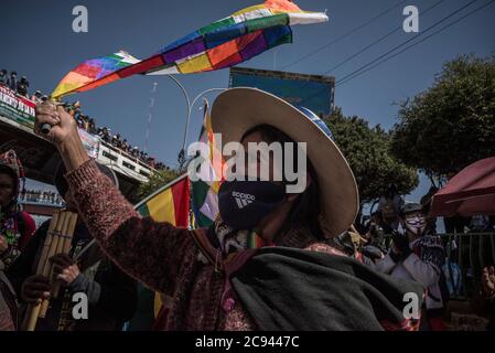 28 juillet 2020, Bolivie, El Alto: Une femme portant un masque Adidas fait vagues le drapeau d'un peuple autochtone pour protester contre le report renouvelé des élections présidentielles et parlementaires au milieu de la pandémie de Corona. La Cour suprême électorale avait reporté les élections prévues pour le 3 mai au 6 septembre, puis au 18 octobre, en raison de la pandémie. Après la réélection du Président Morales, le 20 octobre 2019, le pays était rioteux. Morales avait démissionné sous la pression de l’armée. Il a été accusé de fraude électorale. En Bolivie, un gouvernement intérimaire dirigé par le TH Banque D'Images