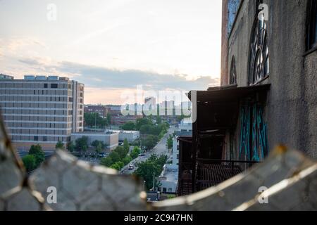 Vue sur une fenêtre brisée dans un grand bâtiment abandonné dans une rue animée de la ville et Skyline Banque D'Images