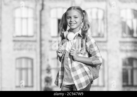 bonne humeur par temps. vacances de printemps ou d'été. temps libre avec de la musique. appareil numérique pour les enfants avancés. hipster positif enfant en morceaux d'oreille. petite fille souriante au soleil porter sac à dos. Banque D'Images