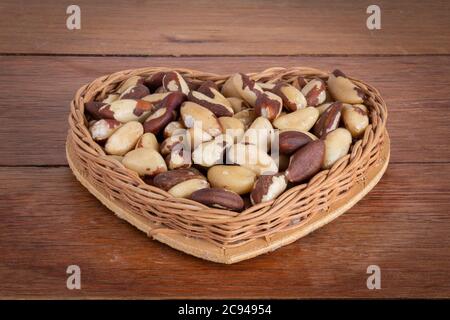 La noix brésilienne, connue sous le nom de 'Castanha do Pará' dans un panier en forme de coeur sur une table en bois Banque D'Images