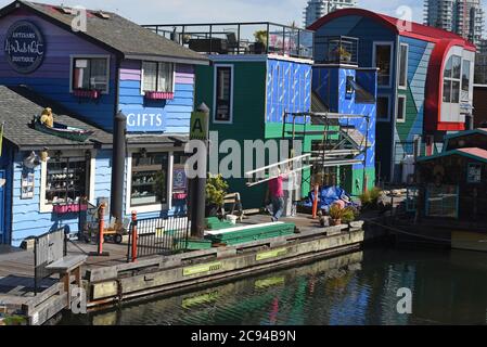 Un ouvrier porte une échelle devant une boutique de cadeaux flottante et des flottomes à Fisherman’s Wharf à Victoria, en Colombie-Britannique, au Canada, sur l’île de Vancouver. Fi Banque D'Images