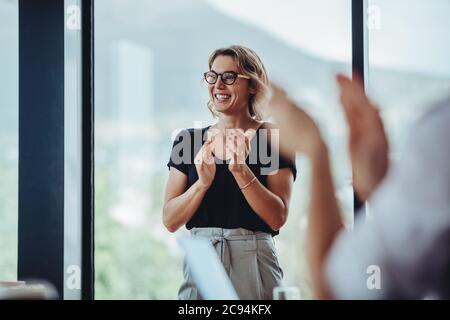 Une femme d'affaires se claque les mains après une séance de brainstorming réussie dans la salle de réunion. Les gens d'affaires applaudissent les femmes après une réunion productive. Banque D'Images