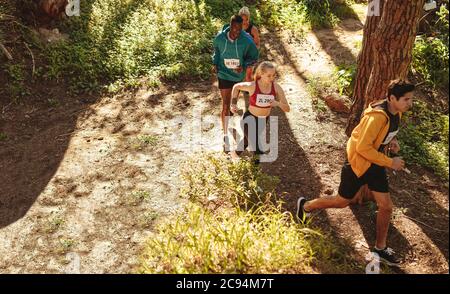 Vue en grand angle des athlètes masculins et féminins qui coutent sur un sentier de montagne. Athlètes professionnels en compétition dans une course de cross-country. Banque D'Images