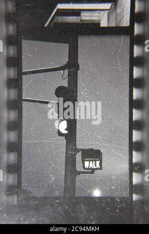 Fin années 1970 vintage noir et blanc photographie d'un feu de circulation clignotant vert et le signal de marche. Banque D'Images