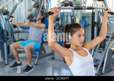 Fitness fille s'entraîner sur les épaules et le haut du dos à l'appareil de tirage de lat, entraînement de force à la salle de gym Banque D'Images