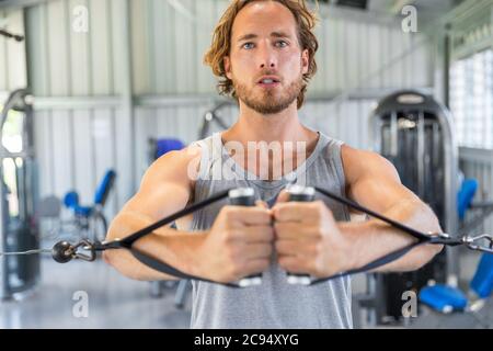 Homme entraînement de force dans la salle de gym faire le câble debout voler sur tour de fitness Banque D'Images