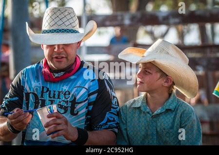 Un rodéo expérimenté s'arrête pour apprécier un en-cas et profiter d'un moment de calme avec un cowboy junior adoring au Mt Garnet, dans le Queensland, en Australie. Banque D'Images