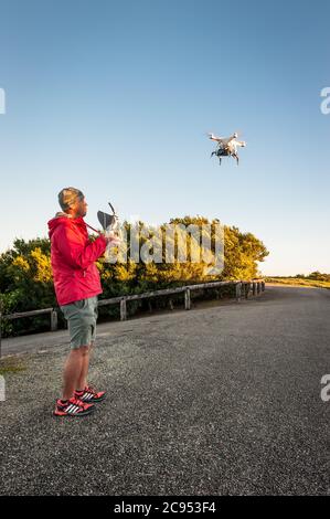 Un pilote de drone en blouson rouge sur un recce photographique pilote son drone sur Windy Hill à Ravenshoe, Queensland en Australie. Banque D'Images