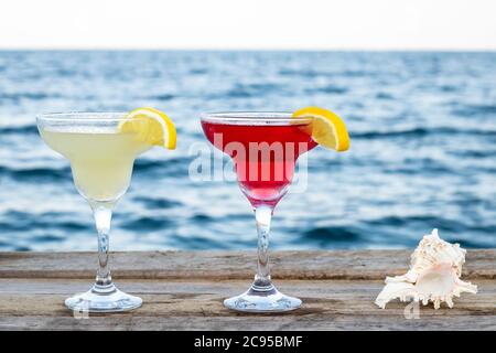 Deux cocktails doux d'été au bord de la mer. Cosmopolite et Marguerite dans un verre sur la jetée. Boissons alcoolisées mélangées. Concept de fête sur la plage, loisirs Banque D'Images