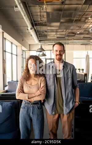 Portrait d'un jeune couple positif de propriétaires de café debout ensemble dans l'établissement de loft Banque D'Images