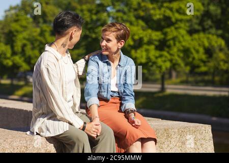 Deux jeunes femmes se rencontrent dans le parc où elles s'assent et discutent entre elles Banque D'Images