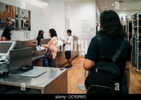 Bangkok, Thaïlande - 3 août 2020 : les clients asiatiques en file d'attente paient leurs vêtements au comptoir de la boutique de vêtements en crise pandémique Covid-19. Banque D'Images