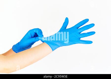 Photo d'une femme mettant des gants en latex bleu sur un fond blanc Banque D'Images