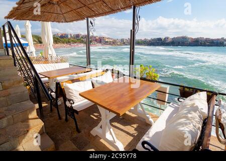 terrasse vide d'un restaurant sur la mer. belle vue sur la baie sous la lumière du matin. parasol décoratif au-dessus des tables et des sièges en bois. weat ensoleillé Banque D'Images