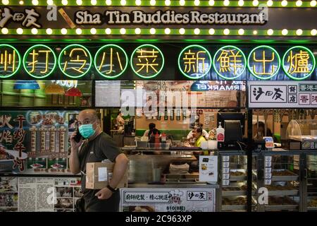 Un homme portant un masque chirurgical marche dans un restaurant du quartier Sha Tin. L'été 2020 est marqué par les scènes liées à la pandémie du coronavirus. Masques chirurgicaux et avertissements interdisant aux personnes d'accéder au scénario. Banque D'Images