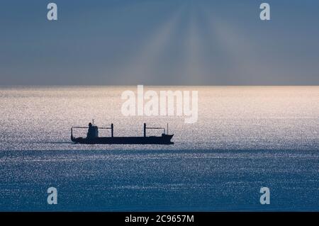 Navire de cargaison silhoueté en mer. Banque D'Images