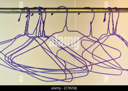 Groupe de cintres de vêtements en fil violet vides suspendus sur le rail. Banque D'Images