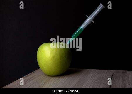 Pomme verte sur une planche en bois et seringue à l'intérieur pour extraire le liquide vert Banque D'Images