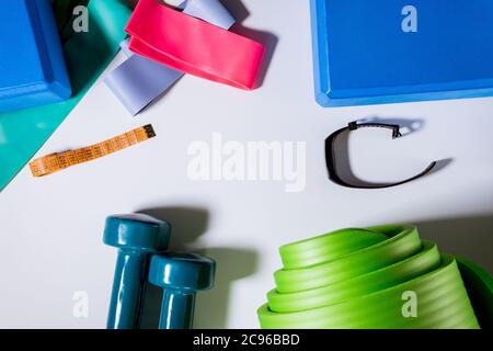 Set pour haltères de yoga, bracelet de fitness, tracker, expandeurs élastiques, bloc de yoga, tapis de yoga, sur fond blanc. La vue du dessus Banque D'Images