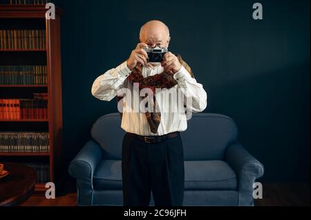 Un écrivain âgé tient un appareil photo rétro au bureau Banque D'Images