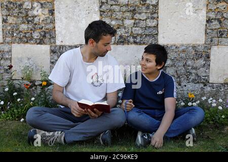 Frères lisant la bible dans un jardin d'église à Eure, France. Banque D'Images