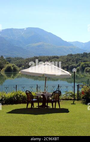 Les tables d'un hôtel pour le petit déjeuner au bord du lac. Vue sur le lac de Scandarello, à Amatrice, dans la province de Rieti, en Latium, en Italie. Le ciel bleu dedans Banque D'Images