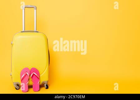 sac de voyage avec tongs roses isolées sur fond jaune Banque D'Images