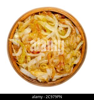 Oignons, rôtis au brun doré, dans un bol en bois. Tranches d'oignons blancs, frits dans de l'huile pour obtenir une belle couleur et un arôme total. Allium lcpe. Gros plan par le dessus Banque D'Images