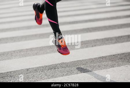 Sautez et gelez dans l'air. Fille de vêtements de sport et de baskets court le long de la transition le long de la route Banque D'Images